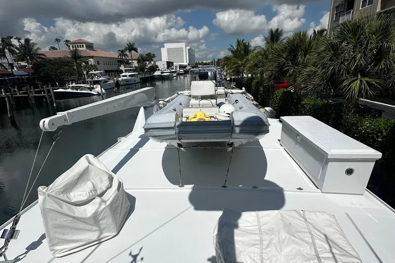 Adventurer Yacht Photos Pics Luxury yacht deck with inflatable boat, docked in a marina, surrounded by palm trees.