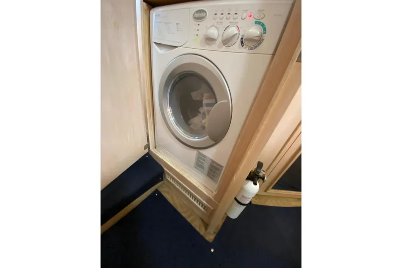 Sea Trial Yacht Photos Pics Laundry area inside 1991 Hatteras 40 Motor Yacht, featuring a compact washing machine.