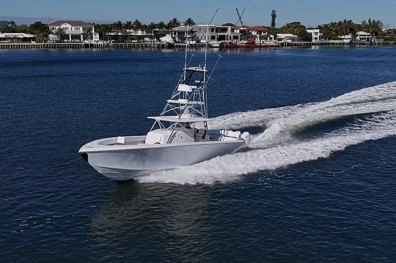  Yacht Photos Pics A 2025 Sparks 46 boat cruising on a calm waterfront with houses in the background.
