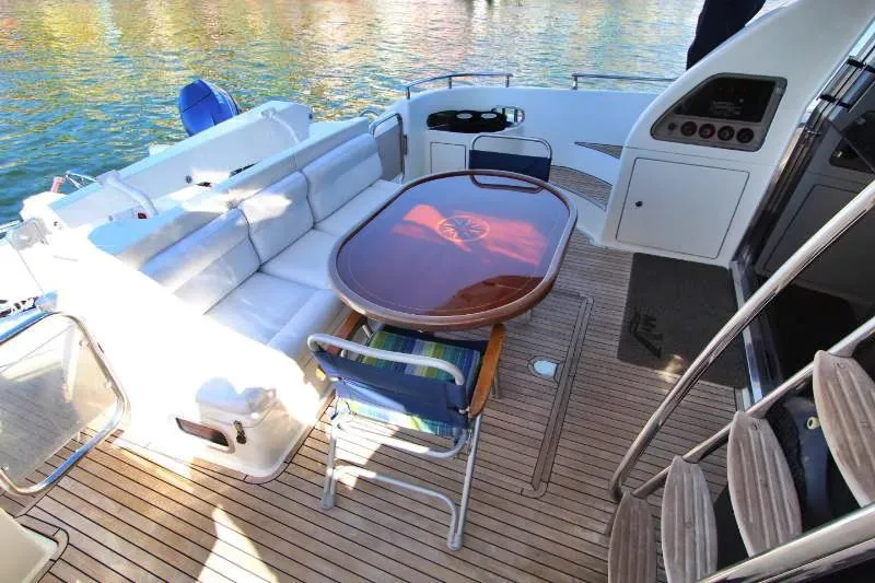 Yacht Photos Pics 1999 Azimut 58 yacht deck with seating, table, and wooden flooring.