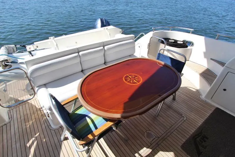  Yacht Photos Pics Luxury Azimut 58 yacht deck with elegant wooden table, cushioned seating, and ocean view.