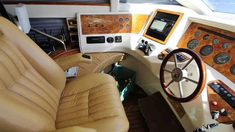  Yacht Photos Pics 1999 Azimut 58 yacht helm with leather seat, wooden steering wheel, and control panel.