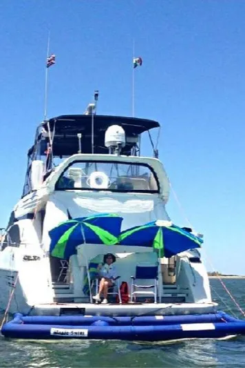  Yacht Photos Pics 1999 Azimut 58 yacht with umbrellas on deck, anchored in calm waters.