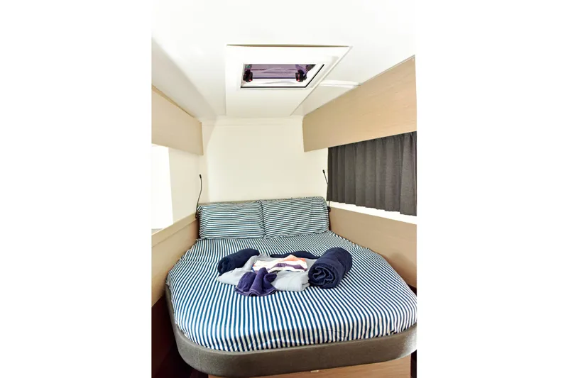 Boomerang Yacht Photos Pics Cozy cabin interior of 2022 Fountaine Pajot Astrea 42 with striped bedding and skylight.