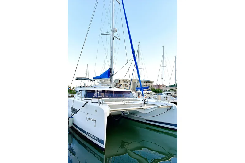 Boomerang Yacht Photos Pics 2022 Fountaine Pajot Astrea 42 catamaran docked in a marina, featuring sleek design and blue sail.