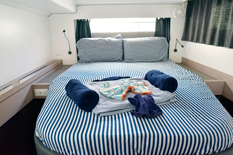 Boomerang Yacht Photos Pics Luxurious cabin interior of 2022 Fountaine Pajot Astrea 42 with striped bedding and towels.