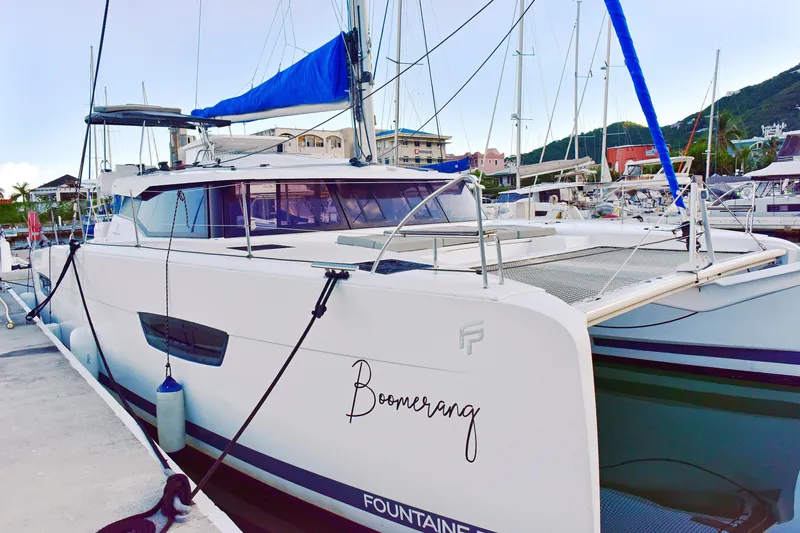 Boomerang Yacht Photos Pics 2022 Fountaine Pajot Astrea 42 catamaran docked at marina, featuring sleek design and blue sail.