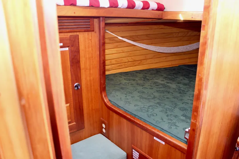 Mangata Yacht Photos Pics Cozy cabin interior of 1997 Valiant 39 sailboat with wooden finish and green bedding.