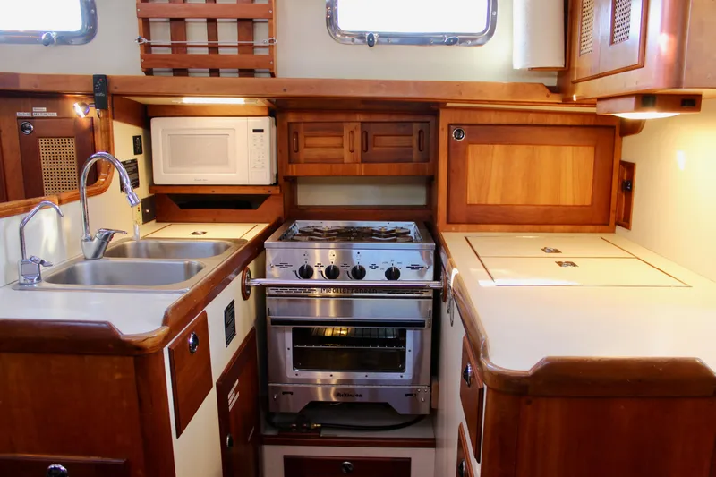 Mangata Yacht Photos Pics 1997 Valiant 39 yacht kitchen with stove, sink, and microwave in wooden cabinetry.