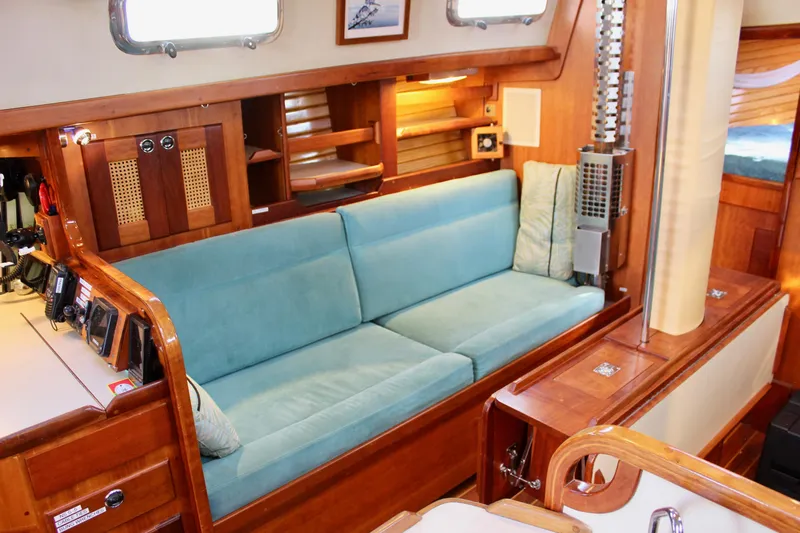 Mangata Yacht Photos Pics Interior of 1997 Valiant 39 yacht with teal sofa and wooden cabinetry.