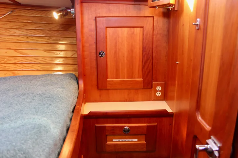 Mangata Yacht Photos Pics Wooden interior of 1997 Valiant 39 sailboat with bed, cabinet, and electrical outlet.