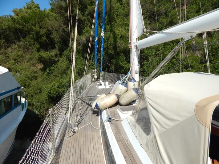  Yacht Photos Pics Sailboat deck of 1992 Tayana 55 with rigging and fenders, surrounded by lush greenery.