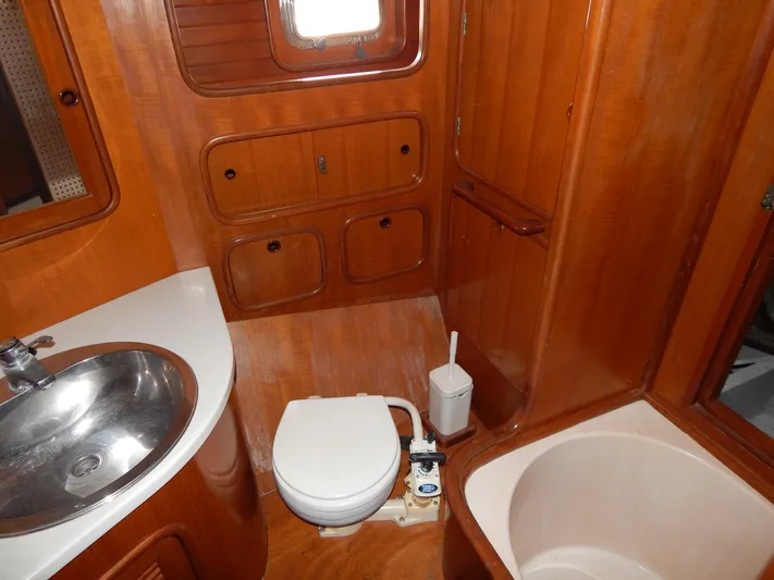  Yacht Photos Pics 1992 Tayana 55 yacht bathroom with wooden cabinetry, sink, toilet, and bathtub.