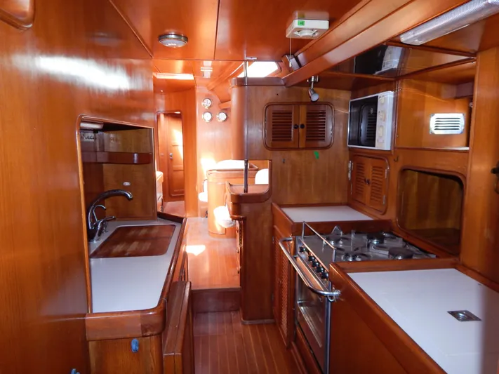  Yacht Photos Pics Interior of 1992 Tayana 55 yacht, featuring a wooden galley with stove, sink, and microwave.
