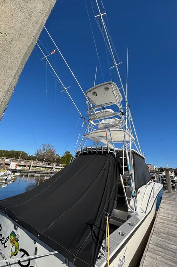 Reel Deal Yacht Photos Pics 2001 Carolina Classic 35 boat with fishing rods, docked under clear blue sky.