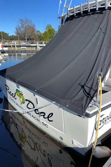 Reel Deal Yacht Photos Pics 2001 Carolina Classic 35 boat docked with black cover, named "Reel Deal," in sunny marina.