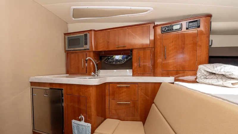  Yacht Photos Pics 2012 Regal 35 Sport Coupe interior kitchen with wood cabinets, microwave, and compact fridge.