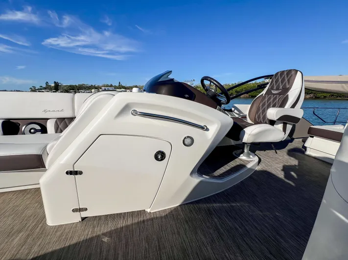  Yacht Photos Pics 2021 Bennington 27 QX boat interior with steering wheel and seating, under clear blue sky.