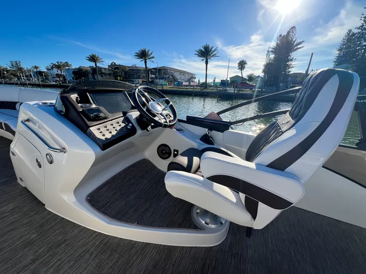  Yacht Photos Pics 2021 Bennington 27 QX boat interior with steering wheel and captain's chair, sunny waterfront view.