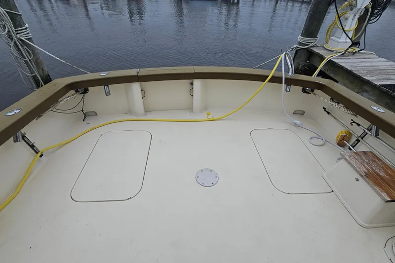 Tizzylizzy Yacht Photos Pics 1989 Post 43 Convertible boat deck with yellow cables, docked by the water.