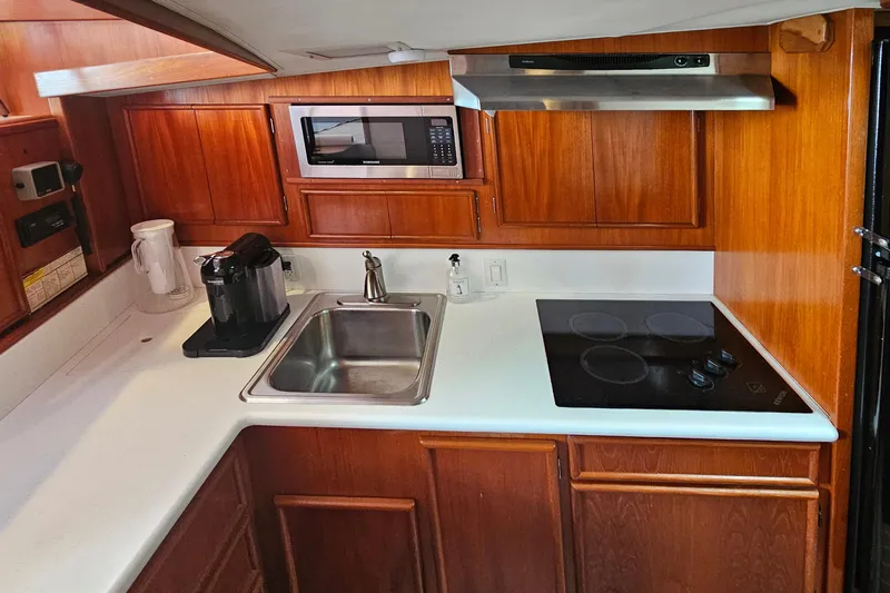 Tizzylizzy Yacht Photos Pics 1989 Post 43 Convertible yacht kitchen with wooden cabinets, sink, stove, and microwave.
