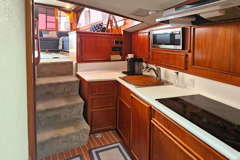 Tizzylizzy Yacht Photos Pics 1989 Post 43 Convertible yacht interior with wooden cabinetry, kitchenette, and carpeted stairs.