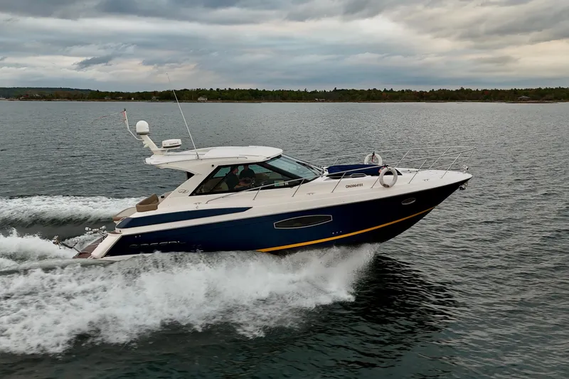 Knot Seine Yacht Photos Pics 2013 Regal 42 Sport Coupe cruising on a lake under cloudy skies.