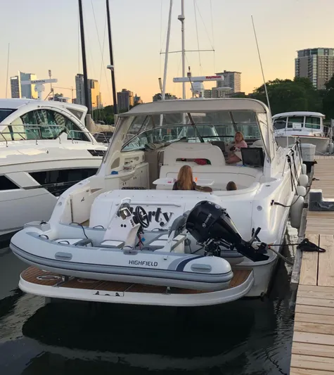 Kaboom Yacht Photos Pics 2000 Sea Ray 460 Sundancer docked, featuring a Highfield tender, with city skyline in the background.