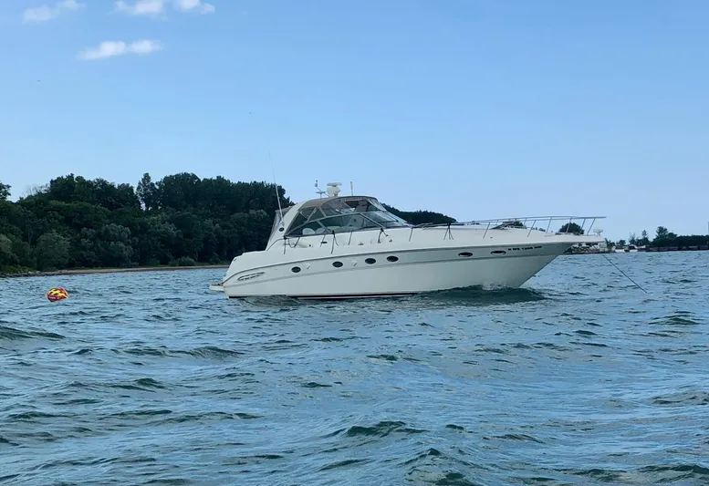 Kaboom Yacht Photos Pics 2000 Sea Ray 460 Sundancer yacht on calm water near a forested shoreline.