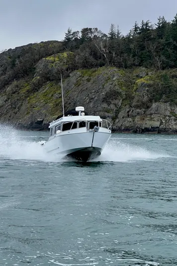  Yacht Photos Pics 2015 River Hawk SH Offshore XL boat cruising near rocky shoreline.