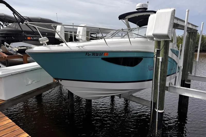  Yacht Photos Pics 2021 Regal 26 XO boat in blue, docked on a lift at a marina.