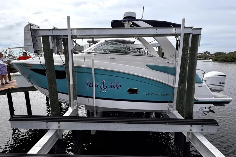  Yacht Photos Pics 2021 Regal 26 XO boat on lift, turquoise and white design, docked by water.