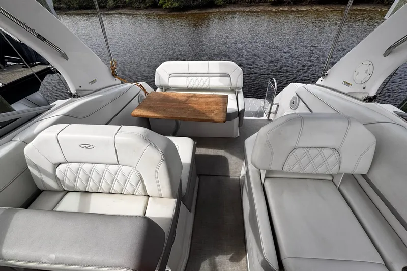  Yacht Photos Pics 2021 Regal 26 XO boat interior with white seating and wooden table by the water.
