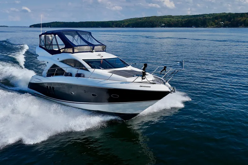 Why Not Yacht Photos Pics 2005 Sunseeker Manhattan 50 yacht cruising on a serene lake under a clear sky.