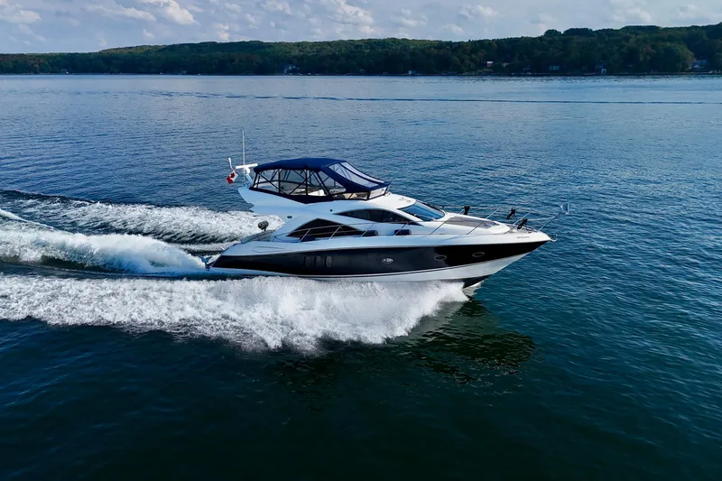 Why Not Yacht Photos Pics 2005 Sunseeker Manhattan 50 yacht cruising on a serene lake under a cloudy sky.