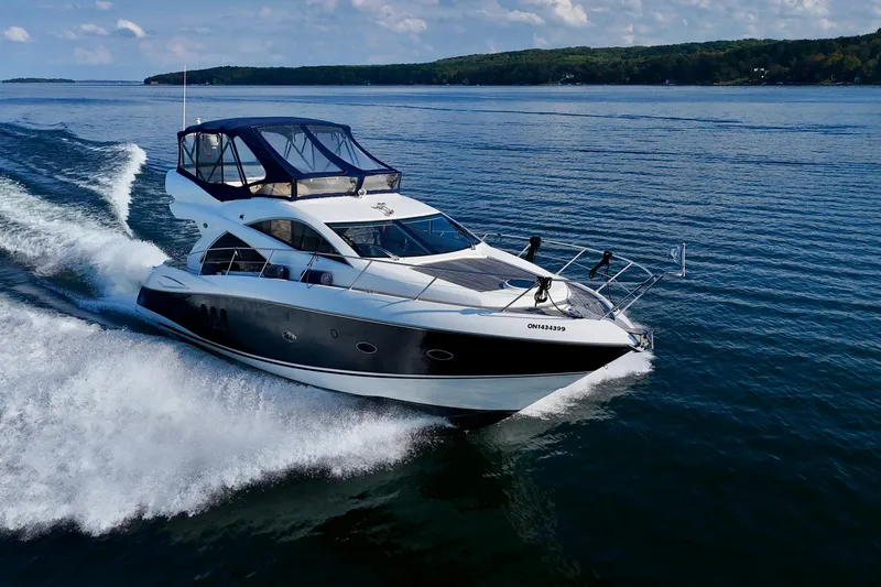 Why Not Yacht Photos Pics 2005 Sunseeker Manhattan 50 yacht cruising on a serene lake under a clear sky.