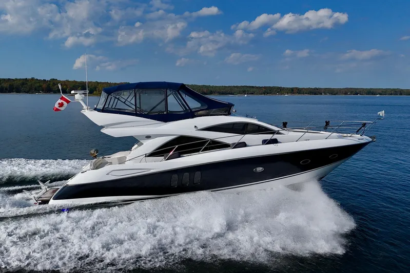 Why Not Yacht Photos Pics 2005 Sunseeker Manhattan 50 yacht cruising on a lake under a clear blue sky.