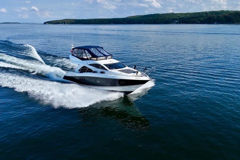 Why Not Yacht Photos Pics 2005 Sunseeker Manhattan 50 yacht cruising on a serene lake under a clear sky.