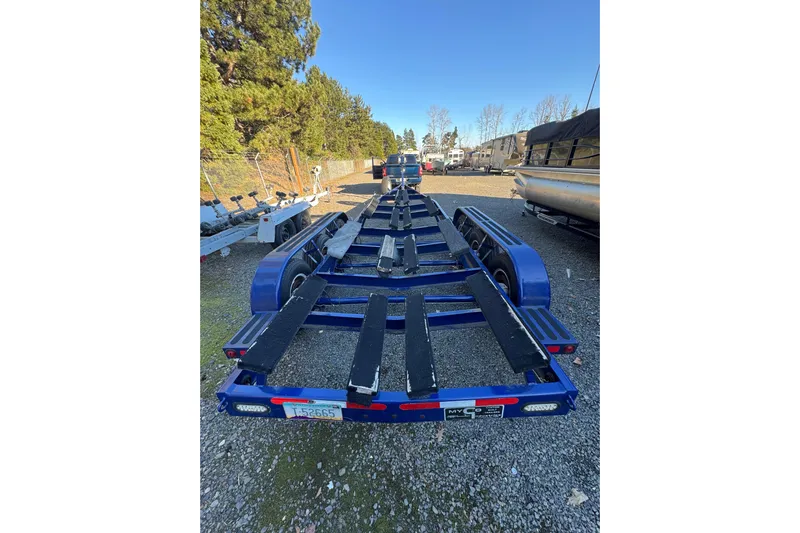  Yacht Photos Pics Blue boat trailer for 2008 Intrepid 327, parked on gravel lot with trees in background.