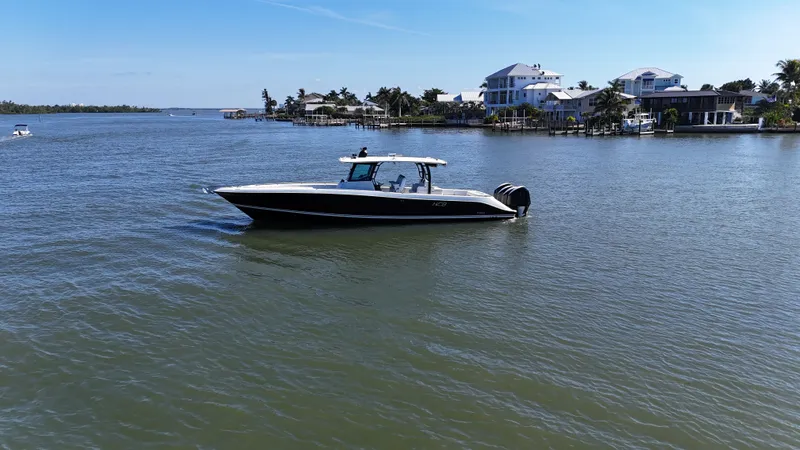  Yacht Photos Pics 2018 HCB 42 Siesta boat on calm water near coastal homes.