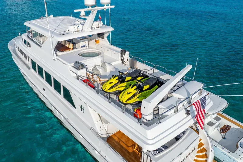 Done Deal Yacht Photos Pics Luxurious 2010 Hargrave Raised Pilothouse yacht with jet skis on deck, cruising in clear blue waters.