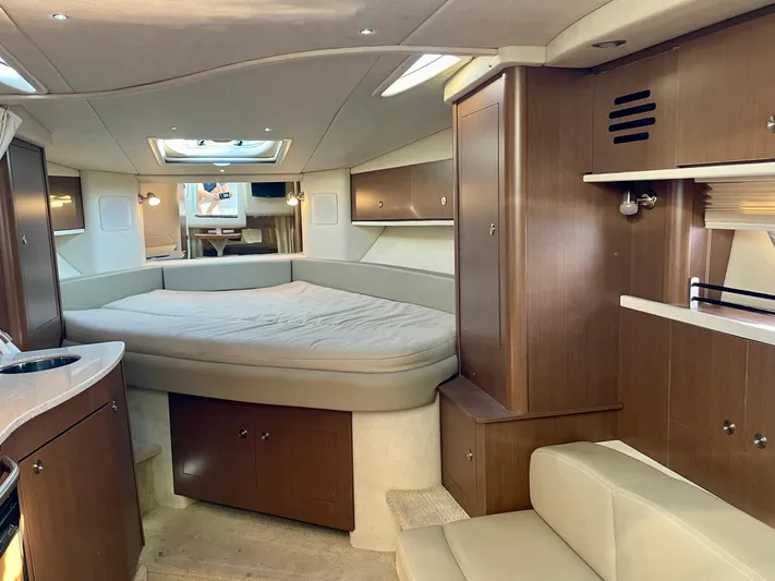 Ilaria Yacht Photos Pics 2014 Sea Ray 330 Sundancer cabin interior with bed, wood cabinetry, and seating area.
