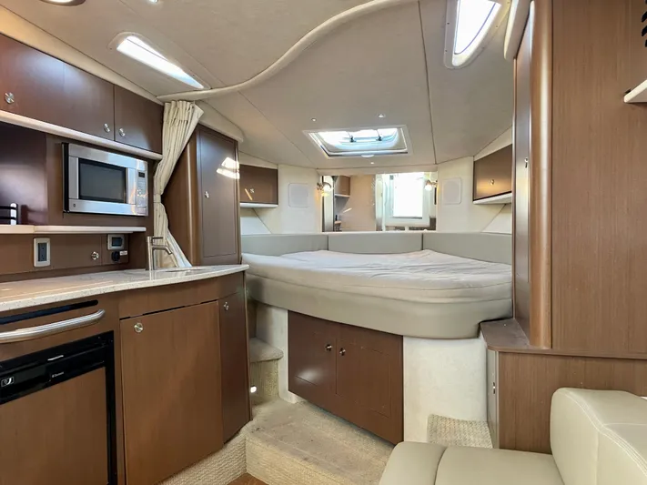 Ilaria Yacht Photos Pics 2014 Sea Ray 330 Sundancer cabin interior with bed, kitchenette, and wood cabinetry.