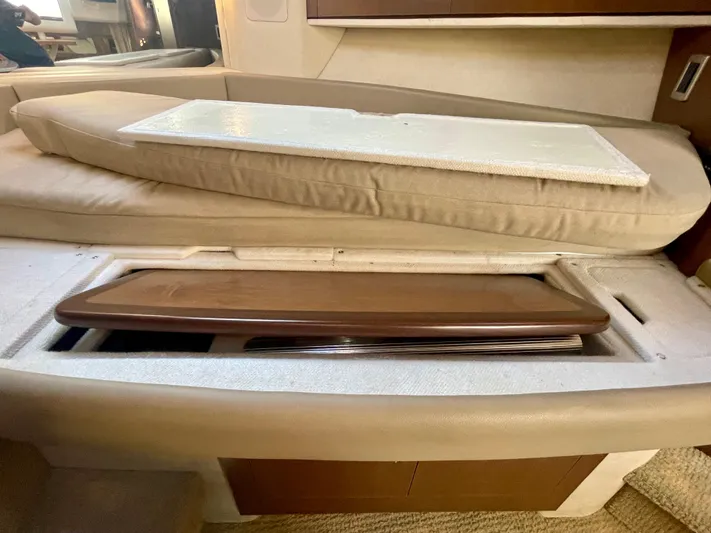 Ilaria Yacht Photos Pics 2014 Sea Ray 330 Sundancer interior storage compartment with beige cushions and wooden panel.