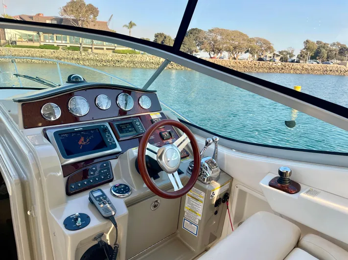 Ilaria Yacht Photos Pics 2014 Sea Ray 330 Sundancer cockpit with modern controls and scenic waterfront view.