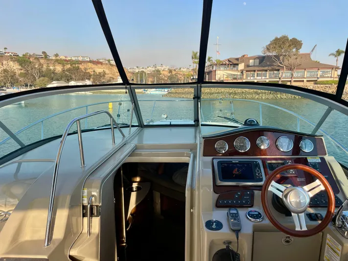Ilaria Yacht Photos Pics 2014 Sea Ray 330 Sundancer cockpit with steering wheel and control panel, docked in a marina.