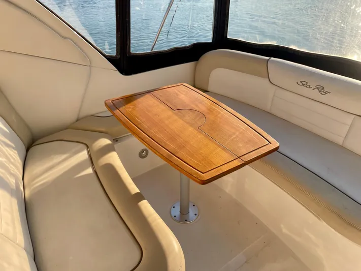 Ilaria Yacht Photos Pics 2014 Sea Ray 330 Sundancer interior with wooden table and cushioned seating.
