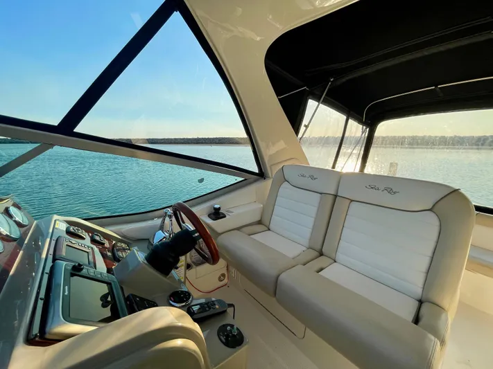 Ilaria Yacht Photos Pics 2014 Sea Ray 330 Sundancer interior with beige seating and helm, overlooking serene water.