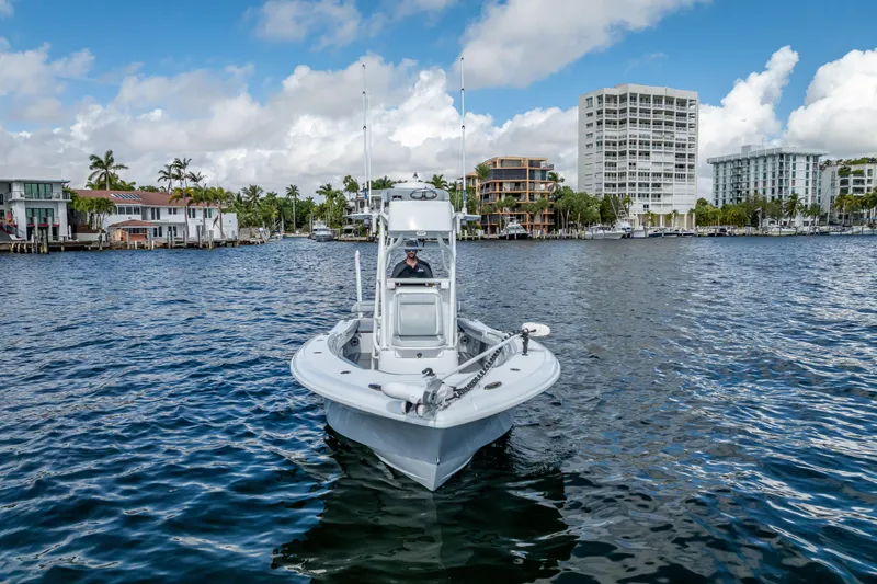  Yacht Photos Pics 2021 Yellowfin 26 Hybrid boat cruising on a scenic waterfront with buildings in the background.