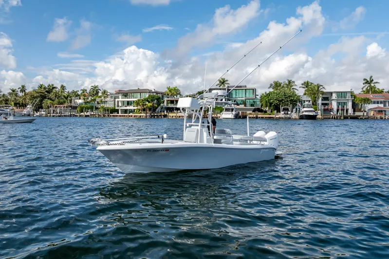  Yacht Photos Pics 2021 Yellowfin 26 Hybrid boat on water, with waterfront homes in the background.